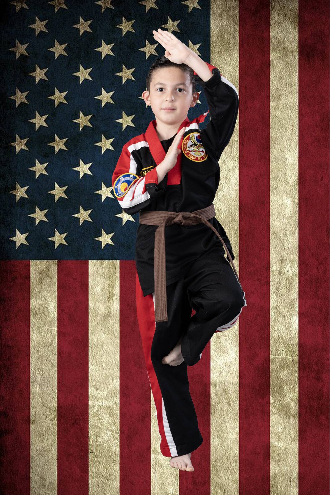 Student in a clean traditional martial arts portrait, saluting in front of an American flag